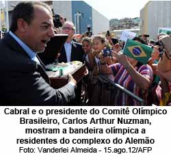 Cabral e o presidente do Comit Olmpico Brasileiro, Carlos Arthur Nuzman, mostram a bandeira olmpica a residents do complexo do Alemo  - Foto: Vanderlei Almeida - 15.ago.12/AFP